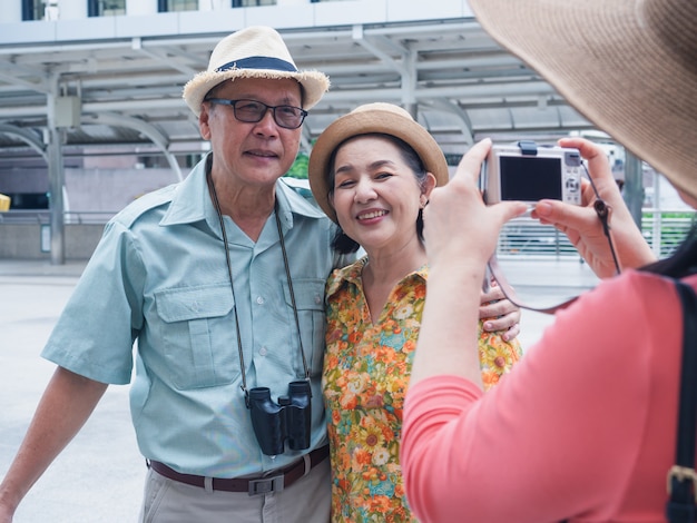 Foto um grupo de idosos em pé e tirando fotos enquanto viaja pela cidade