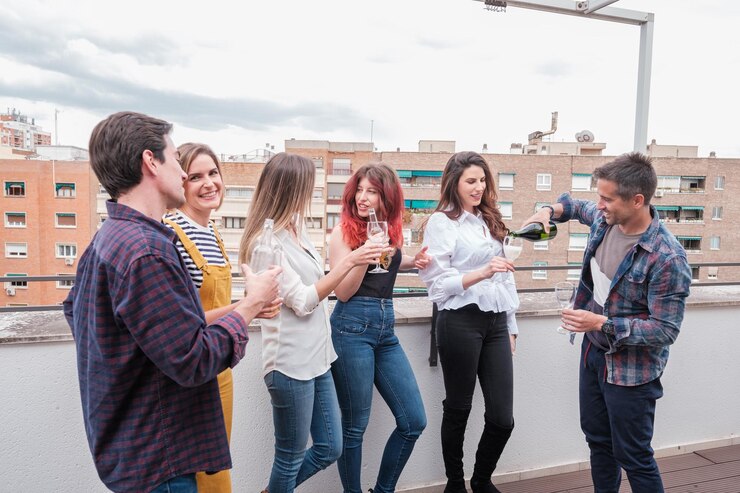 Foto um grupo de jovens amigos a brindar no terraço de uma penthouse.