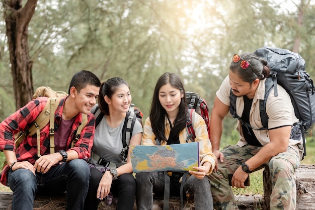 Um grupo de jovens asiáticos está planejando e olhando mapas para acampar na floresta.