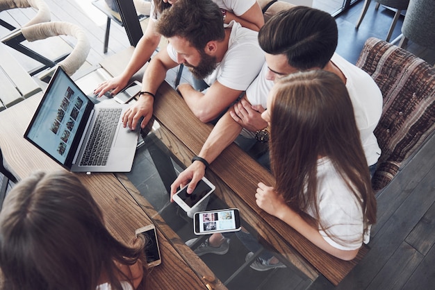 Um grupo de jovens com gadgets e laptop organiza um brainstorm e se comunica. O conceito de desenvolver uma empresa jovem