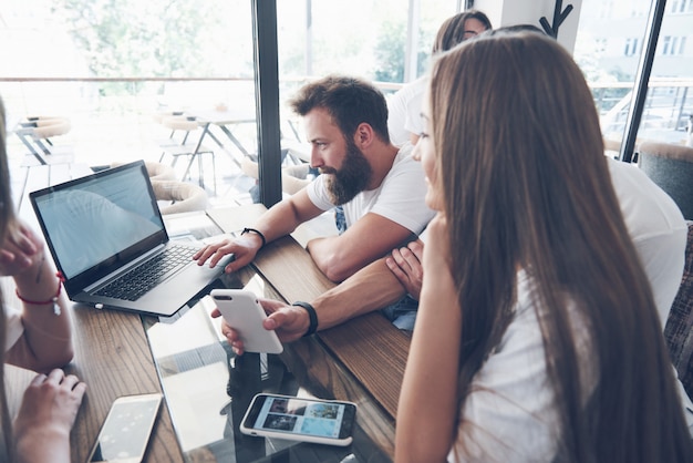 Um grupo de jovens com gadgets e laptop organiza um brainstorm e se comunica. O conceito de desenvolver uma empresa jovem