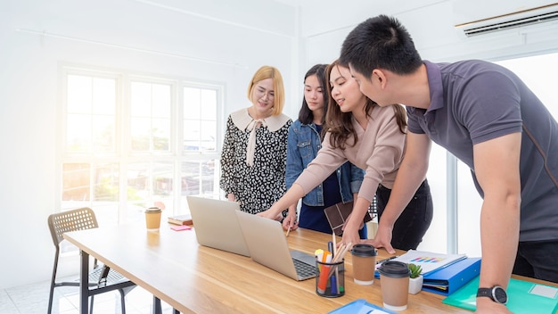 Um grupo de jovens empresários se encontra em um laptop e trabalha em um escritório interno.