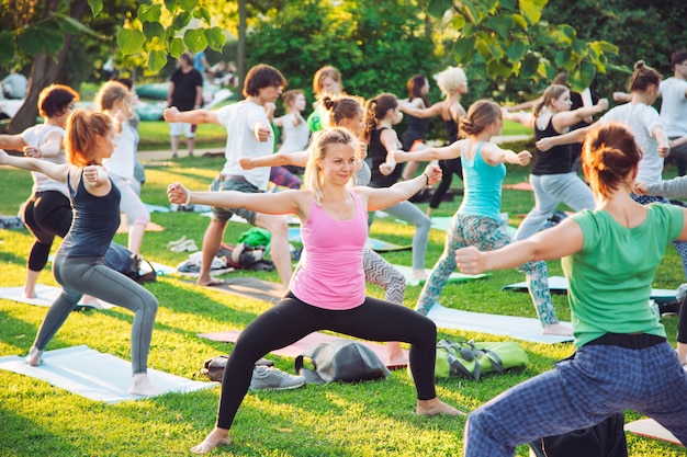 Um grupo de jovens faz ioga no parque ao pôr do sol.