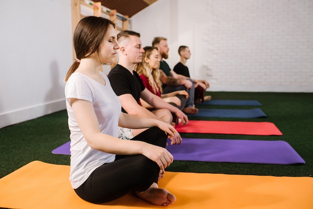 Um grupo de jovens fazendo exercícios joga dentro de casa na academia