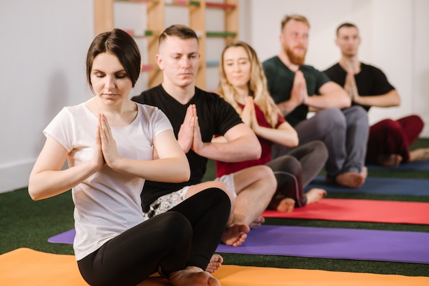 Um grupo de jovens fazendo exercícios joga dentro de casa na academia