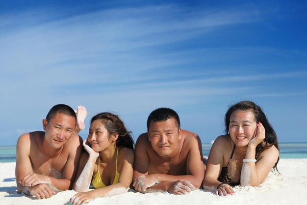 Um grupo de jovens felizes se divertem e se alegram na praia de areia branca num belo dia de verão.