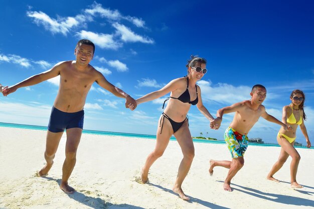 Um grupo de jovens felizes se divertem e se alegram na praia de areia branca num belo dia de verão.