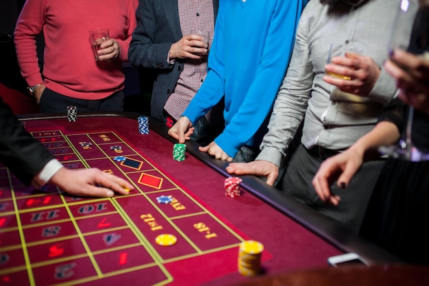 Um grupo de jovens joga roleta de pôquer na mesa Amigos jogando no cassino Apostas