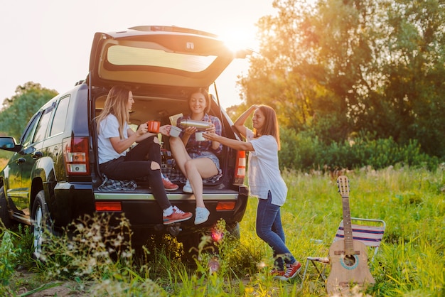 Um grupo de jovens mulheres alegres viaja na natureza de carro