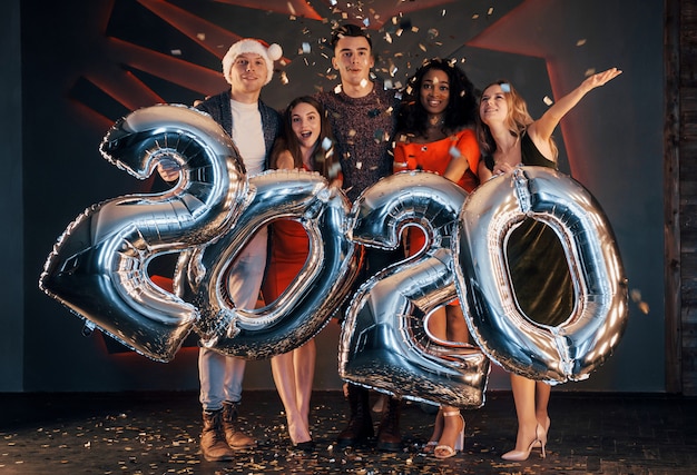 Um grupo de jovens multinacionais bonitas divertidas jogando confete em uma festa. feliz ano novo.