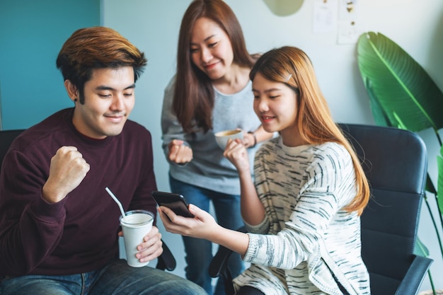 Um grupo de jovens se divertindo e comemorando enquanto assistem no celular juntos