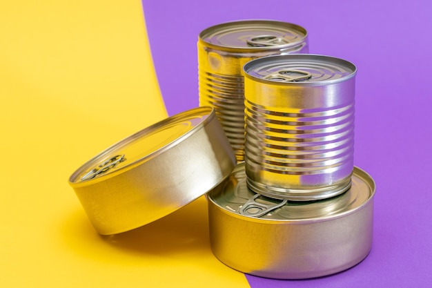 Foto um grupo de latas empilhadas com bordas em branco em um fundo amarelo e violeta dividido