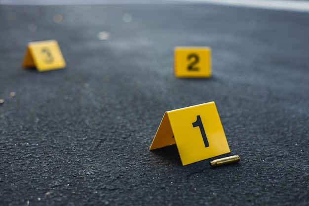 Um grupo de marcadores amarelos de evidências da cena do crime na rua depois de uma arma disparar uma bala de bronze de um rifle