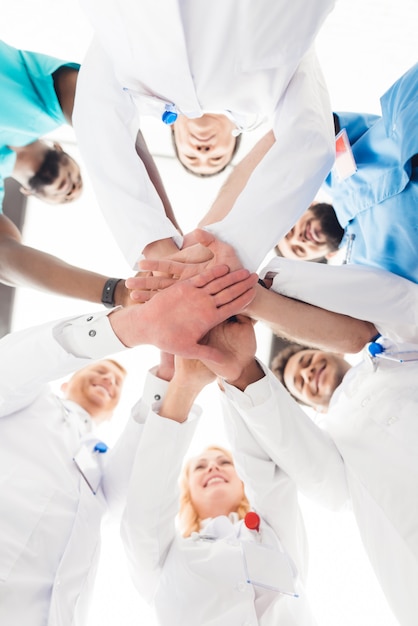 Foto um grupo de médicos está segurando as mãos uns dos outros.