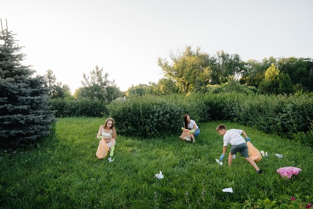 Um grupo de meninas com filhos ao pôr do sol está envolvido na coleta de lixo no parque. Cuidado com o meio ambiente, reciclagem.