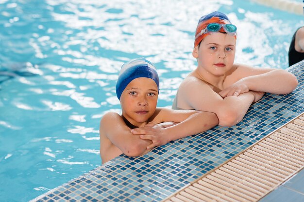 Um grupo de meninos e meninas treina e aprende a nadar na piscina com um instrutor