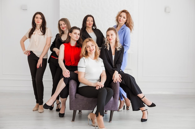 Um grupo de mulheres vestidas com estilo empresarial estão juntos e posando para a câmera.