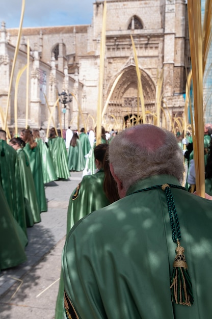 Um grupo de pessoas com túnicas verdes está em fila em frente a uma catedral.