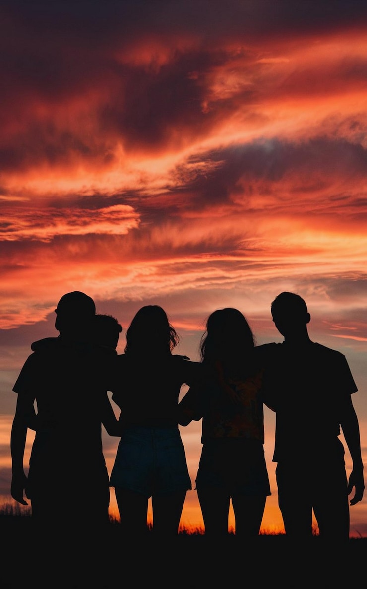 Foto um grupo de pessoas em frente a um céu ao pôr do sol