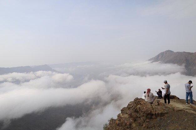 Foto um grupo de pessoas está no topo de uma montanha com uma vista das montanhas