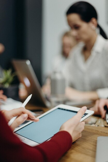 Um grupo de pessoas está sentado em uma mesa com um tablet e uma caneta branca