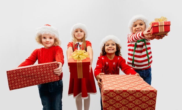 Um grupo de quatro crianças com presentes de Natal em fantasias de Natal