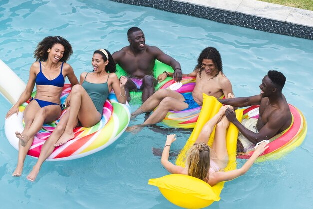 Foto um grupo diversificado de amigos desfruta de uma festa na piscina flutuando em anéis coloridos