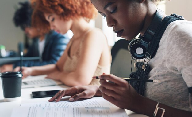 Um grupo diversificado de estudantes lendo a papelada e estudando um jovem estudante lendo seus textos acadêmicos antes de fazer anotações um estudante acadêmico sério lendo seus relatórios enquanto estudava