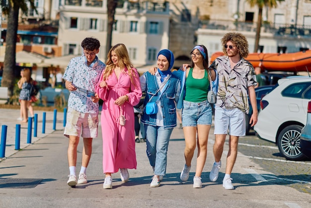 Foto um grupo diversificado de turistas vestidos com trajes de verão passeia pela cidade turística com amplas