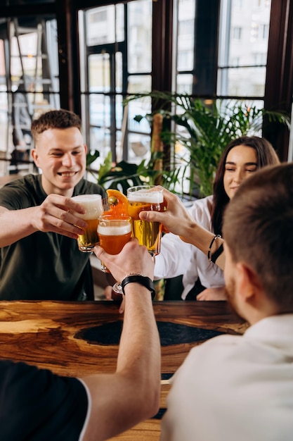 Um grupo feliz de amigos bebendo e tocando com cerveja e coquetéis no bar-restaurante da cervejaria conceito de estilo de vida de bebidas com meninos e meninas se divertindo juntos