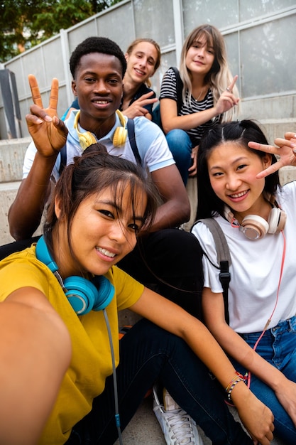 Foto um grupo feliz e sorridente de estudantes multirraciais olhando para a câmera tirando uma selfie imagem vertical