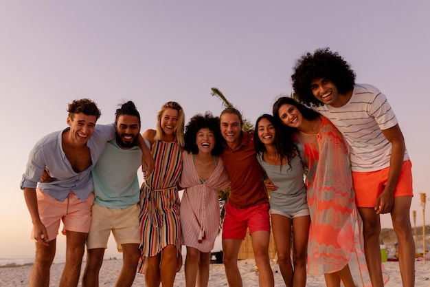 Um grupo multiétnico de amigos aproveitando o tempo juntos, em fila, abraçando-se, olhando para a câmera