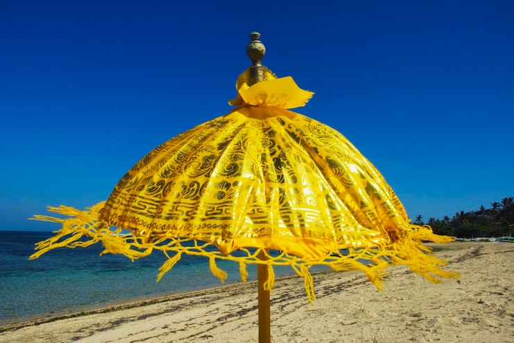 Foto um guarda-chuva amarelo na praia contra um céu azul claro