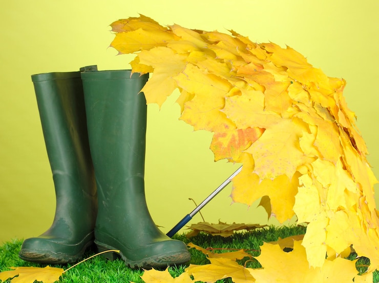 Foto um guarda-chuva de folhas de bordo com botas de goma na grama verde