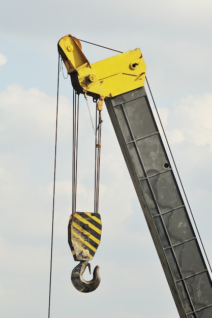 Um guindaste de construção amarelo com gancho contra o céu