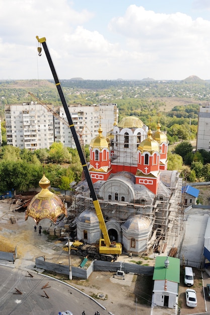 Um guindaste ergue a cúpula dourada da igreja ortodoxa. Construção e reconstrução da igreja.