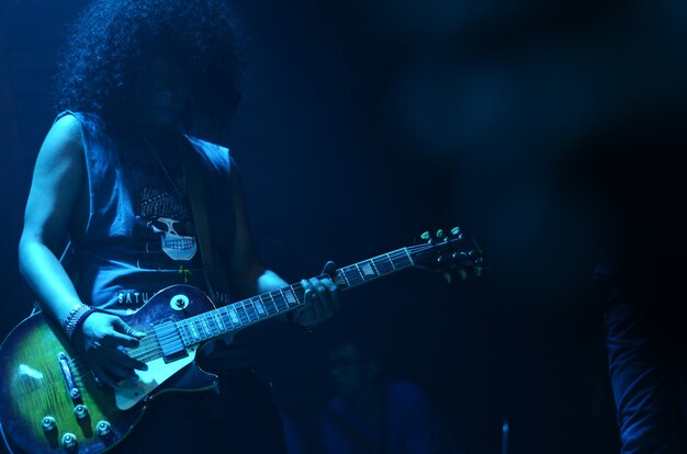 Um guitarrista com cabelo crespo com brilho azulado