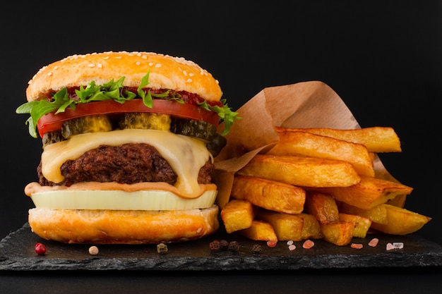 Um hambúrguer clássico grande e alto em uma placa de pedra preta