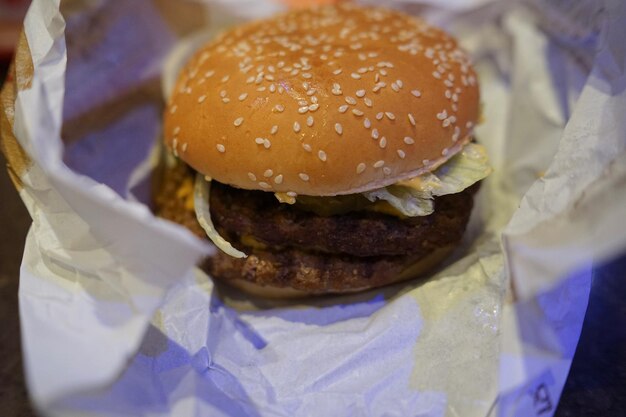 Foto um hambúrguer grande e desembalado num restaurante de comida rápida.