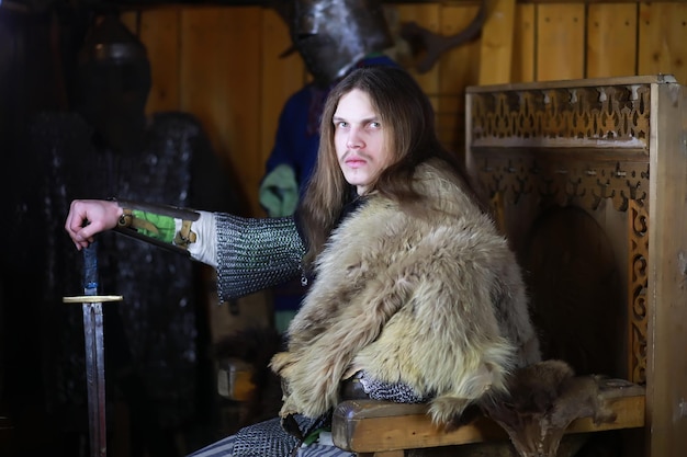 Um herói poderoso com cabelo comprido em armadura de cota de malha em um antigo salão. Guerreiro medieval nas câmaras do cavaleiro.