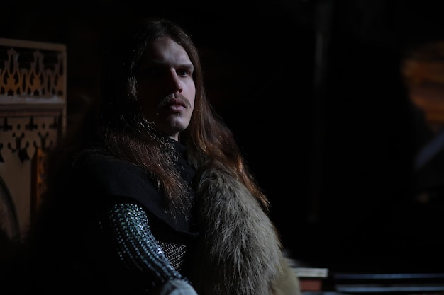 Um herói poderoso com cabelos longos em armadura de cota de malha em um antigo salão guerreiro medieval nas câmaras do cavaleiro