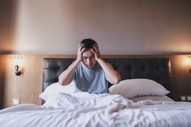 Um homem acorda do sono e sente dor de cabeça ou enxaqueca