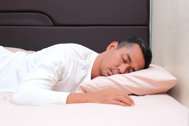 Foto um homem adulto asiático a dormir de barriga para baixo.