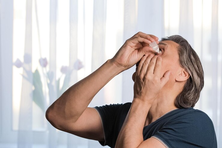 Foto um homem adulto de cabelos grisalhos está a derramar gotas para os olhos.