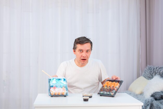 Foto um homem adulto faminto com descrença e surpresa segura sushi da entrega em suas mãos