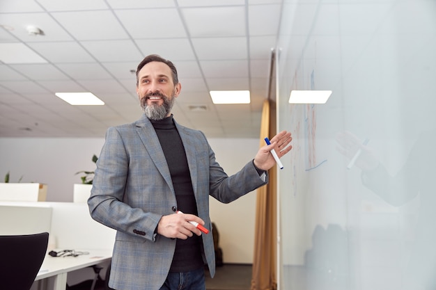 Foto um homem adulto no escritório escrevendo na mesa de vidro