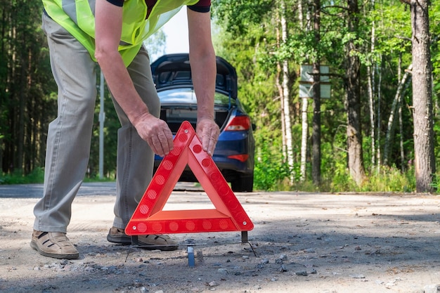 Um homem adulto posiciona um triângulo de advertência triangular vermelho reflexivo