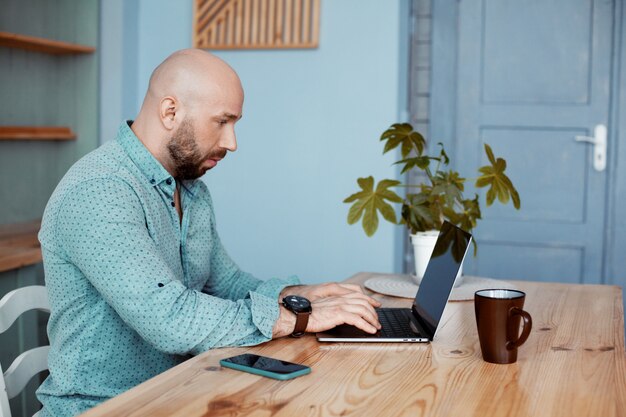 Um homem adulto trabalha no computador durante o café da manhã, trabalha em casa