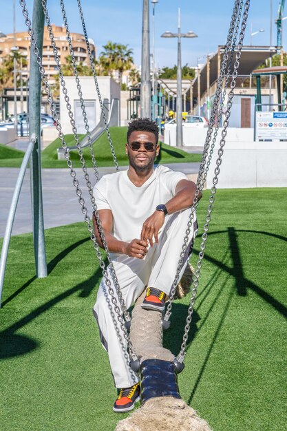 Um homem afro-americano sentado em um baloiço em um parque público