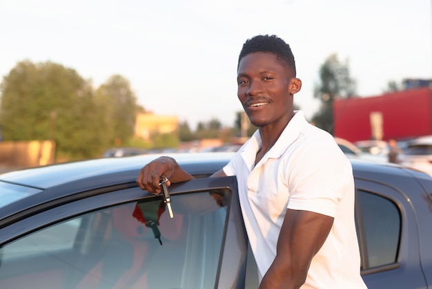 Um homem afro-americano sorridente segura as chaves do carro em suas mãos Concessionária de carros Indústria automotiva